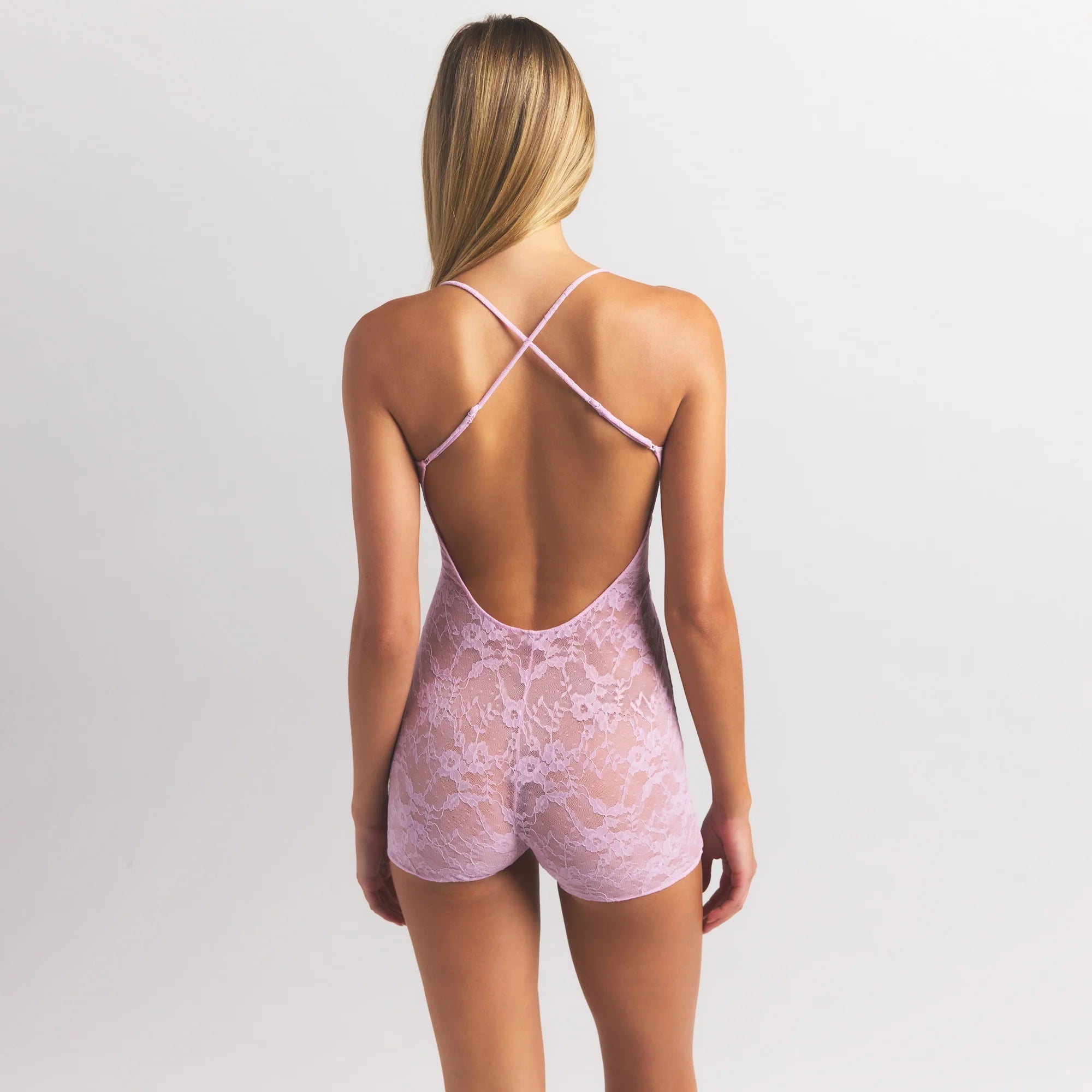 STRETCH LACE LOW BACK ONESIE | BABY PINK ON A MODEL SIDE VIEW @ | FOCUS: 0.0, 1.0, 0.9